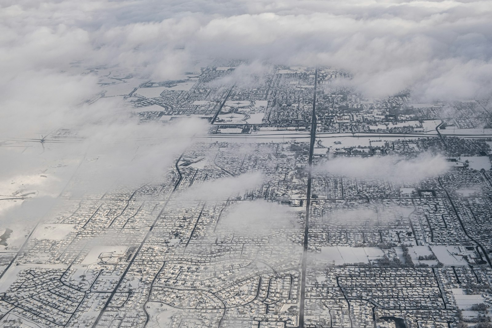 an aerial view of a city blanketed in winter haze below the mountains