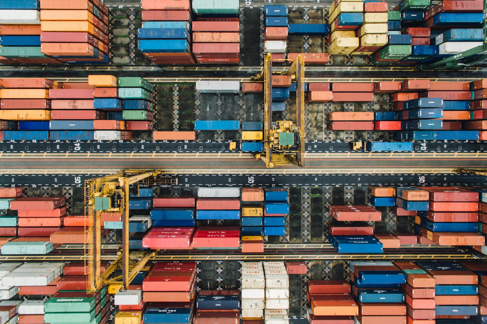 An aerial view of colorful shipping containers stacked in a busy industrial port