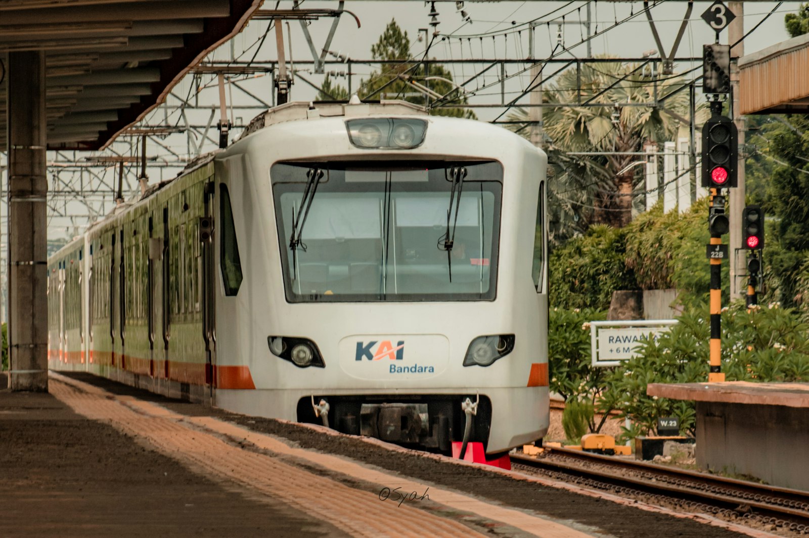 a white train traveling down train tracks next to a train station